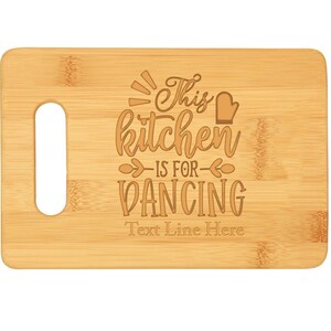 May include: A brown bamboo cutting board with a handle and the text "This kitchen is for dancing" engraved on it. The text "Text Line Here" is also engraved on the board.