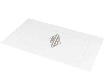 May include: White bath mat with a gray embroidered monogram "MB" in a diamond shape.
