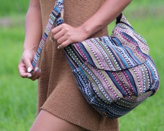 May include: A woman wearing a brown sleeveless dress with a colorful patterned shoulder bag. The bag has a long strap and is worn across the body.