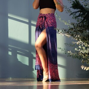 May include: A woman wearing a black crop top and a long, blue and pink patterned skirt with a side slit. The skirt has a tie at the waist and a mandala design.
