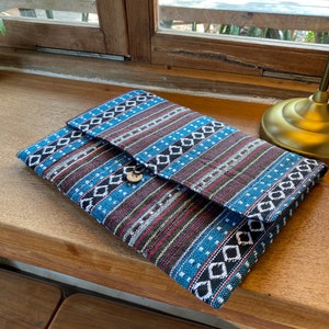 May include: A blue and brown patterned fabric clutch with a wooden button closure.