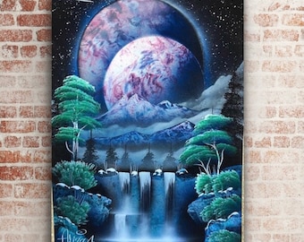 May include: A spray paint artwork depicting a waterfall cascading down a mountain range with a double planet in the background. The sky is black with white stars and a comet. The planets are pink, blue, and purple.