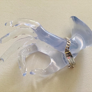 K&ouml;nnte beinhalten: Ein silbernes Armband mit Kettenglied-Design und einem rechteckigen Anh&auml;nger. Der Anh&auml;nger tr&auml;gt die Worte "Forever & Always" und ein Blumenmuster. Das Armband wird auf einem transparenten, handf&ouml;rmigen Display pr&auml;sentiert.