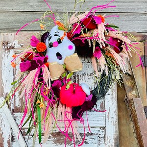 May include: A pink and white ghost with a pink pumpkin and pink and burgundy flowers on a wreath.