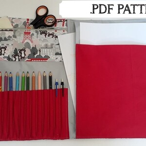 Könnte beinhalten: Eine rote und graue Stoff-Bleistiftrolle mit Reißverschlussfach und Griff. Die Rolle hat ein Muster mit Bären, Fahrrädern und Gebäuden. Die Rolle ist geöffnet und zeigt einen Satz Buntstifte und einen Stift. Die Rolle ist mit "PDF PATTERN" beschriftet.