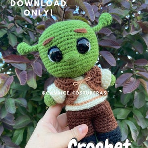 May include: A crochet pattern for a green ogre amigurumi doll. The doll is wearing a brown vest and brown pants. The text "Crochet Pattern!" is written in white letters on a green background.