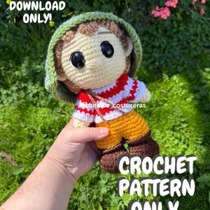May include: A handmade crochet doll with a green hat, cream-colored face, and large black eyes. The doll wears a red and white striped shirt, yellow pants, and brown boots. Text on the image reads "PDF DOWNLOAD ONLY!" and "CROCHET PATTERN ONLY".