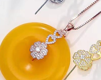 May include: A yellow circular jade-like pendant attached to a rose gold chain, featuring a flower-shaped bail encrusted with clear stones. Three additional silver and gold-toned flower-shaped bails with clear stones are arranged around the pendant.