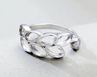 Könnte beinhalten: Ein silberfarbener offener Ring mit einem Band, das aus einer Reihe von miteinander verbundenen, hohlen, blattförmigen Metallsegmenten besteht. Ein Ende des Rings ist mit einem kleinen, klaren, rund geschliffenen Stein besetzt.