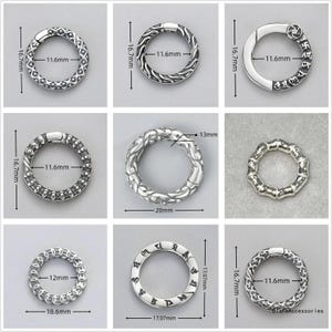 May include: A collection of nine silver-toned circular spring gate rings with various embossed patterns and engravings. Each ring features a hinged opening mechanism. Dimensions are clearly marked, showing diameters ranging from 11.6mm to 20mm.