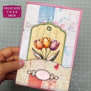 May include: A folio-sized card (7 x 4.5 inches) with a pink border and a floral design. The card features a decorative tag with three tulips in orange, purple, and yellow. The bottom of the card has a pink oval embellishment.