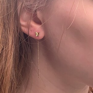 May include: A gold butterfly charm earring with a delicate chain dangling from the bottom.