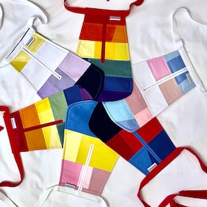 May include: Six colourful patchwork fabric pouches with white straps and zips. Each pouch features a different colour combination of rainbow colours.