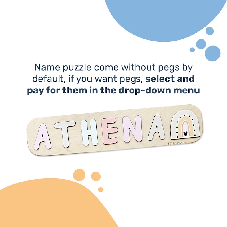 以下が含まれることがあります： パステルピンク、白、青の文字でATHENAと書かれた木製の名前パズルで、最後には虹の形が添えられています。テキスト：Name puzzle come without pegs by default, if you want pegs, select and pay for them in the drop-down menu.