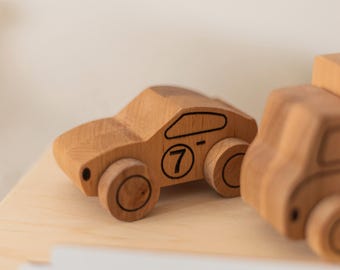 Könnte beinhalten: Holzspielzeugauto mit der schwarzen Zahl 7 auf der Seite. Das Auto ist aus hellem Holz gefertigt und hat schwarze Details an Rädern und Fenstern. Das Spielzeugauto steht auf einer hellen Holzoberfläche.