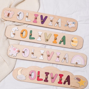 May include: Wooden name puzzles spelling "Olivia" in various pastel colors. Each puzzle features a different decorative element, including a butterfly, bunny, unicorn, and cloud. The puzzles are designed for children.