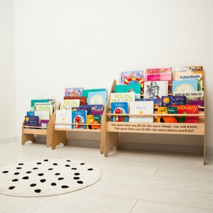 May include: Three wooden bookcases with colorful children's books on shelves. The bookcases are against a white wall and a black and white polka dot rug is in the foreground. The quote "The more that you READ, the more things you will KNOW. The more that you LEARN, the more places you'll GO!" is printed on the front of the largest bookcase.