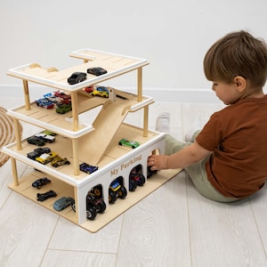K&ouml;nnte beinhalten: Ein mehrst&ouml;ckiges Parkhaus aus Holz mit einer Rampe und mehreren Spielzeugautos. Das Parkhaus besteht aus hellem Holz mit wei&szlig;en Akzenten und tr&auml;gt den Schriftzug "My Parking" auf der Vorderseite.