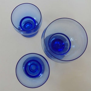 Op de afbeelding: Drie blauwe glazen kommen van verschillende grootte. De kommen zijn helder met een blauwe tint en hebben een afgeronde vorm.