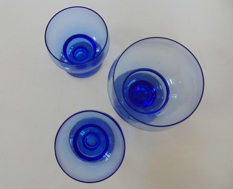 Op de afbeelding: Drie blauwe glazen kommen van verschillende grootte. De kommen zijn helder met een blauwe tint en hebben een afgeronde vorm.