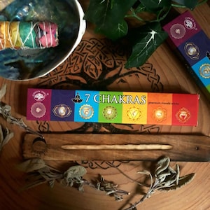 Könnte beinhalten: Eine Schachtel mit 7 Chakra-Räucherstäbchen und einem hölzernen Räucherstäbchenhalter. Die Schachtel hat ein Regenbogen-Design, wobei die sieben Chakren durch verschiedene Farben dargestellt werden. Die Räucherstäbchen sind aus hochwertigem Masala hergestellt.