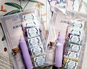Può includere: Un kit per incantesimi d'amore con una candela rosa, una piccola bottiglia di vetro e varie erbe e cristalli. Il kit include petali di rosa, lavanda, salvia e achillea millefolium. Il kit è etichettato "AMO KIT SPELLS" e include istruzioni in francese.