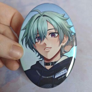 May include: An oval pinback button featuring an anime-style illustration of a character with mint green hair, purple eyes, and a black choker. The character wears a dark hoodie with a silver chain and a tag that reads Favonius in white letters.