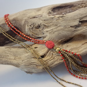 Long necklace in gilded brass and red or orange beads.