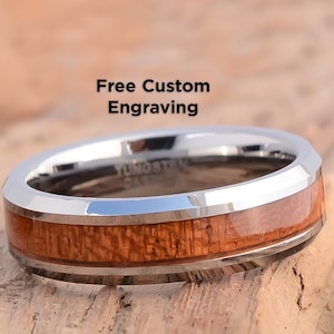 May include: A silver tungsten ring with a brown wood inlay. The ring has a beveled edge and is engraved with the word "Tungsten".