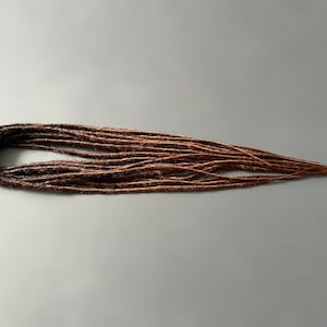 Extensiones de rastas sintéticas con degradado marrón y rastas falsas