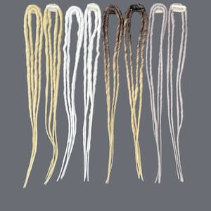 Op de afbeelding: Set van acht nep dreadlock haarverlengingen in verschillende kleuren, waaronder blond, bruin, wit en grijs. Elke verlenging heeft een klein clipje aan de bovenkant voor eenvoudige bevestiging.