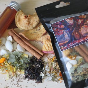 May include: An assortment of autumn-themed items, including a small glass bottle with a silver lid, dried apple slices, cinnamon sticks, and a black bag labeled "THE MAGIC OF AUTUMN". Various herbs and seeds are scattered around the items.