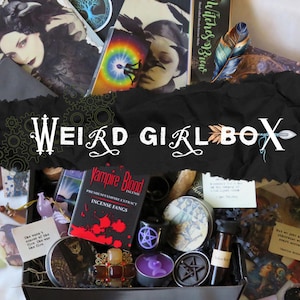 May include: A black box filled with various items, including books, incense, candles, and decorative objects. The box is labeled "Weird Girl Box" in white text. The items have a gothic or witchy theme.