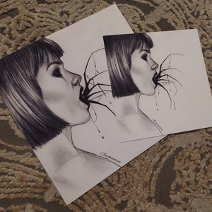 May include: Two black and white pencil drawings of a woman with short hair, her mouth open with a spider crawling out. The drawings are on white paper, with the artist's signature in the bottom right corner. The drawings are placed on a patterned surface.