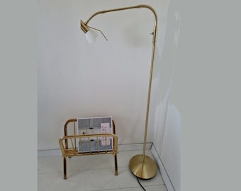 May include: A gold floor lamp with a white shade and a gold magazine rack with a book titled "Joy" on top.