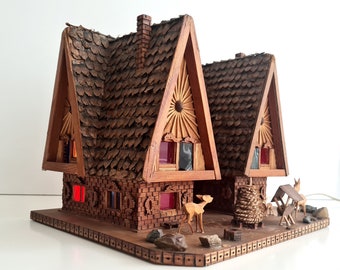 Cabaña vintage de madera tallada a mano con ciervos e iluminación navideña.
