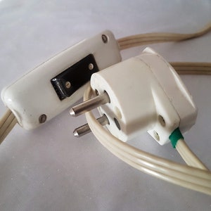May include: A white electrical cord with a white inline switch and a white two-prong plug. The plug has a green grounding wire.