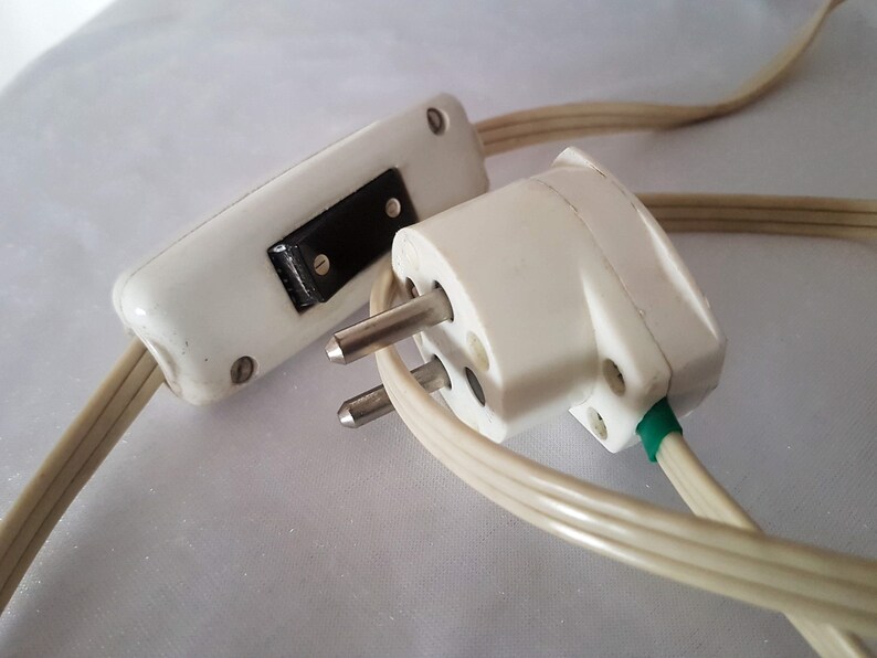 May include: A white electrical cord with a white inline switch and a white two-prong plug. The plug has a green grounding wire.