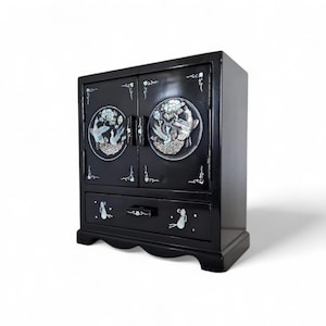 May include: A black wooden cabinet with two doors and a drawer. The doors are decorated with mother-of-pearl inlays of birds and flowers. The drawer has a mother-of-pearl inlay of a bird.