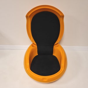 May include: A bright yellow egg-shaped chair with a black fabric cushion. The chair is open and the back is tilted back.