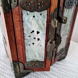 May include: A wooden jewelry box with intricate carvings and a brass lock and key. The box is decorated with jade panels and brass accents.