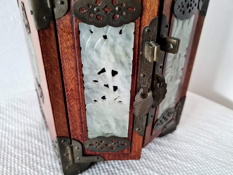 May include: A wooden jewelry box with intricate carvings and a brass lock and key. The box is decorated with jade panels and brass accents.