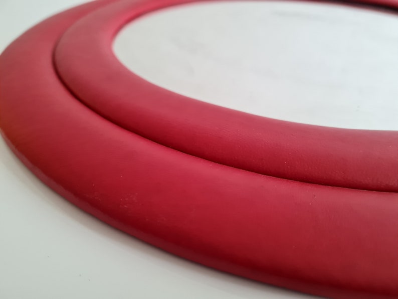 May include: A close-up of a red round mirror with a double-layered frame.