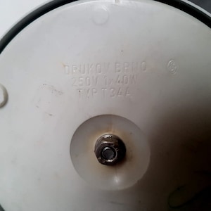 May include: White base of a vintage electric appliance with the text "DRUKOV BRNO 250V 1x40W TYP T34A" printed on it.
