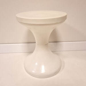 May include: A white plastic stool with a round top and a flared base.