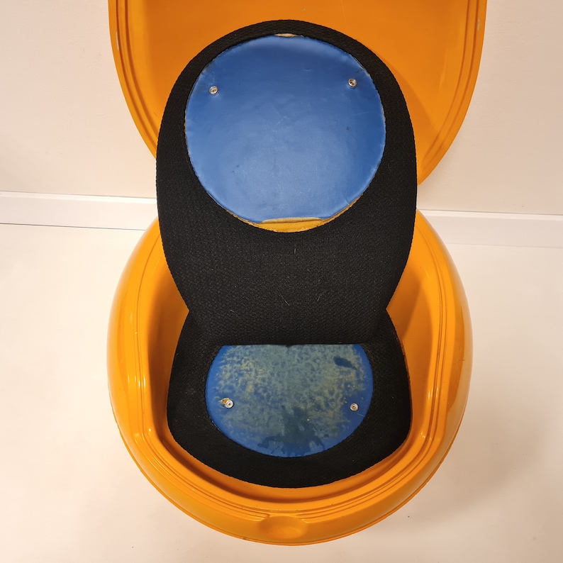May include: A yellow egg-shaped chair with a black and blue padded seat. The chair is open and the top half is flipped back.