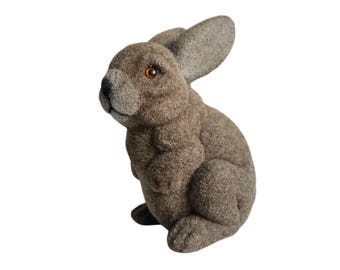 Puede incluir: Una figurita de conejo de peluche marrón con textura esponjosa. El conejo está sentado erguido con las orejas levantadas.