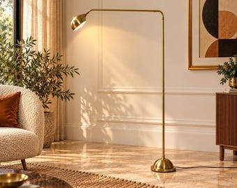 May include: A tall, slender floor lamp with a metallic brass finish, featuring a thin vertical pole, a horizontal adjustable arm, and a dome-shaped shade that emits a warm, focused light downwards from its position in a room.