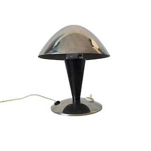 May include: A chrome and black mushroom-shaped table lamp with a round base and a cord.