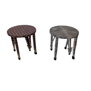 Könnte beinhalten: Zwei dekorative Hocker mit Tiermotiven. Ein Hocker hat einen braunen und cremefarbenen Giraffenprint auf den Beinen und der Sitzfläche. Der andere Hocker hat einen schwarz-weißen Zebraprint auf den Beinen und der Sitzfläche.